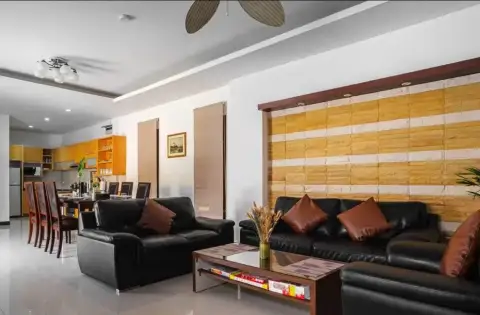 3 Bedroom House for Rent in Na Kluea open-plan living and dining area with black leather sofas and kitchen view