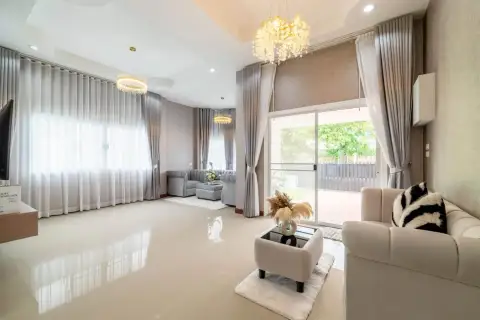 3 Bedroom House for Sale in Nong Pla Lai bright living room with gray sofas and sliding glass door to garden