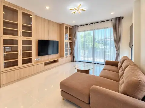 3 Bedroom House for Rent in Nong Prue living area with wood cabinetry, TV unit and sheer curtains