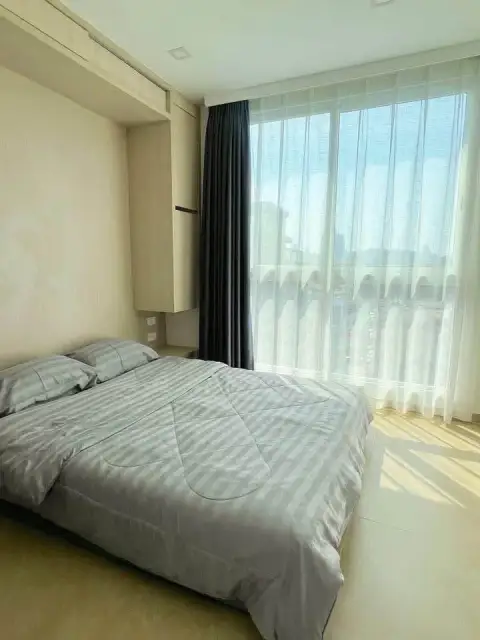 2 Bedroom Condo for Sale at Olympus City Garden bedroom with striped bedding and large window overlooking city