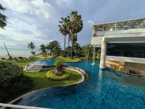 2 Bedroom Condo for Sale at Palm Wongamat infinity pool beside building with ocean and palm trees