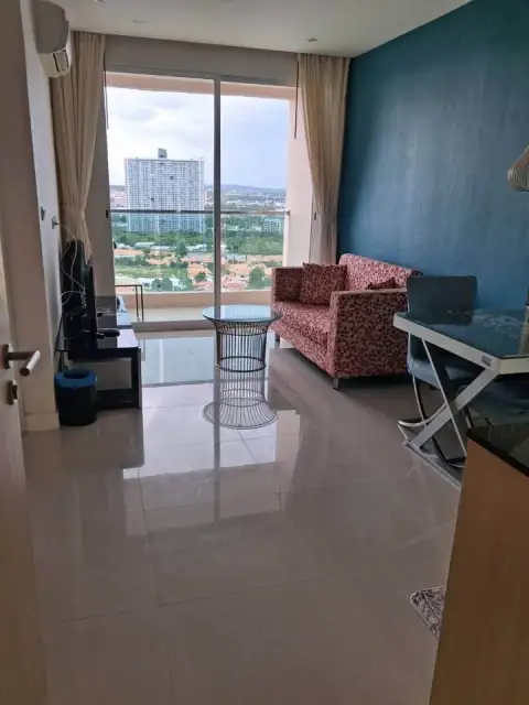 1 Bedroom Condo for Sale at Grande Caribbean living room with pink sofa and balcony city view