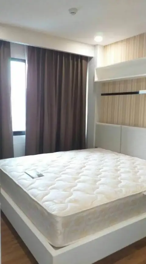 1 Bedroom Condo for Sale in Jomtien bedroom with bare mattress, wooden floor and floating shelf storage