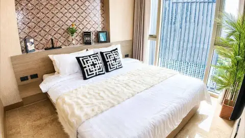 1 Bedroom Condo for Sale at Riviera Ocean Drive bedroom with king bed, patterned headboard, and floor-to-ceiling windows