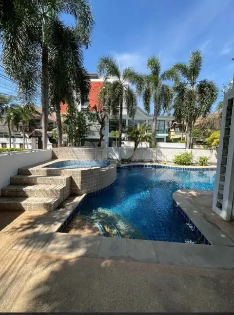 4 Bedroom House for Rent in Central Pattaya featuring curved pool steps with jacuzzi and palm tree landscaping