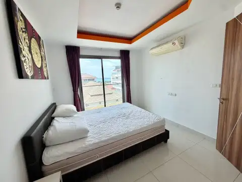 1 Bedroom Condo for Sale at C View Residence 2 bedroom with bed facing window with rooftop and sea view