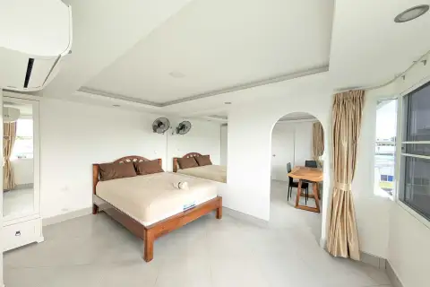 1 Bedroom Condo for Rent at Pattaya Beach Condo bedroom with wooden bed, mirrored wardrobe, and archway to dining area