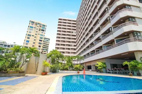 Kieng Talay outdoor swimming pool with surrounding greenery and tall residential buildings under a blue sky.
