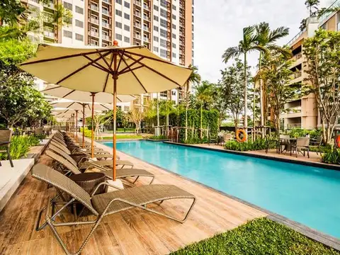 Unixx South Pattaya long outdoor swimming pool with lounge chairs, umbrellas, and surrounding tropical landscaping.