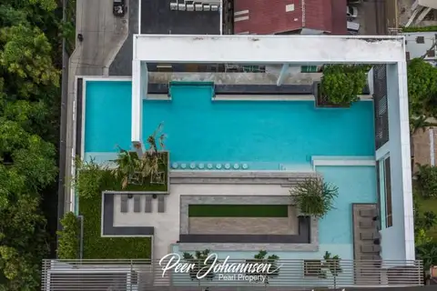 Aeras aerial view of the multi-level swimming pool area with lounge beds and greenery.
