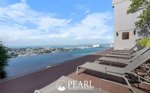 Pattaya Posh rooftop terrace with sun loungers, an infinity pool, and city views.