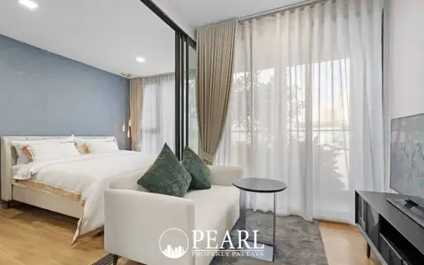 1 Bedroom Condo for Sale at Aquarous Jomtien Pattaya open-plan bedroom with blue accent wall, double bed, sofa, and balcony sliding doors