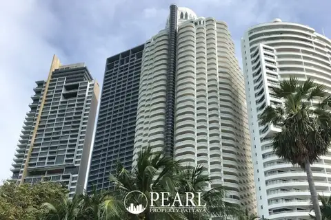 Zire Wongamat three tall condo towers against a blue sky with palm trees in the foreground.
