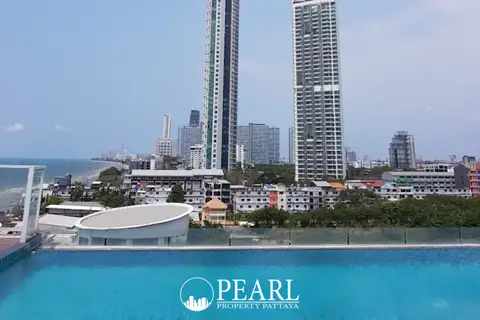 Neo Sea View rooftop pool with city skyline, tall buildings, and ocean in the distance under a blue sky.