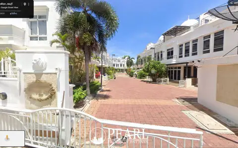 Wongamat Exclusive Place street view of the paved road leading into the residential complex with palm trees.