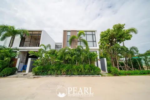 Maxx Pattaya modern white villas with large windows, surrounded by lush green tropical landscaping and palm trees.