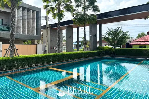 Madcha Nirvana communal swimming pool with blue tiles, surrounded by green hedges and modern architecture.