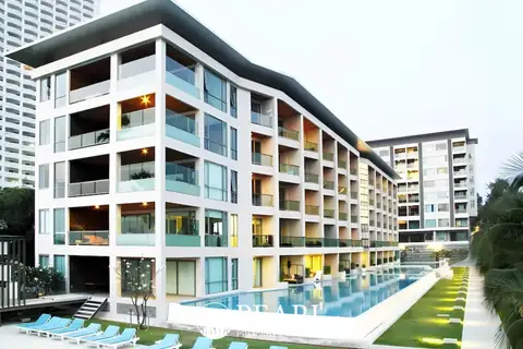 Ananya Beachfront Wongamat exterior of the modern condo building with a long swimming pool and lounge chairs.