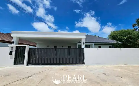 Hillside Village Pattaya modern house exterior from the street, featuring a white wall and a dark gate.