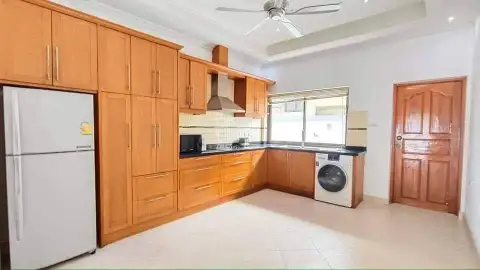 3 Bedroom House for Rent in Jomtien fitted kitchen with wooden cabinetry, fridge, and washing machine