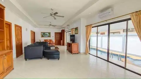 3 Bedroom House for Rent in Jomtien open-plan living room with black sofa, TV, and pool view windows