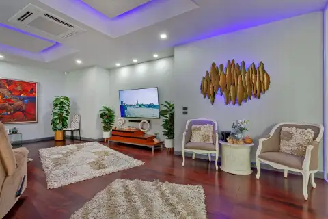 5 Bedroom House for Sale & Rent in Pratumnak Hill lounge area with gold sculptural wall art, accent chairs, LED purple ceiling and large TV