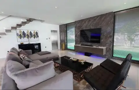 7 Bedroom House for Sale & Rent in Pratumnak Hill living room with gray sectional sofa, marble wall and mounted TV