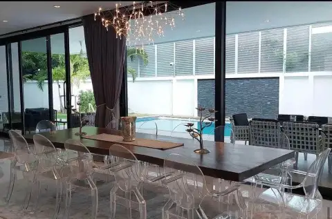 7 Bedroom House for Sale & Rent in Pratumnak Hill dining area with acrylic chairs, wood table and pool view through glass doors