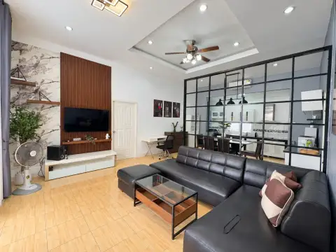 3 Bedroom House for Rent in Pratumnak Hill living room with black leather sofa, TV wall and glass partition