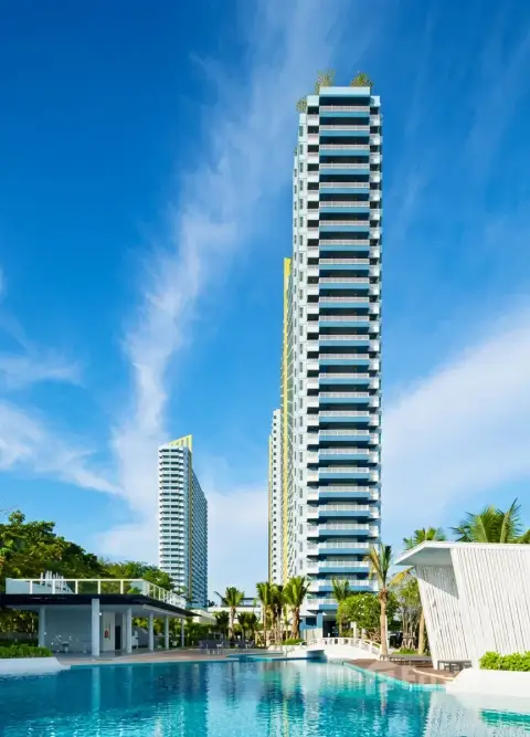Lumpini Park Beach Jomtien tall condo tower exterior with poolside bridge and palm trees