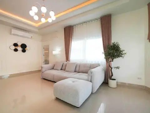 3 Bedroom House for Sale at Raviporn City Home living area with gray sofa, ottoman, and potted plant