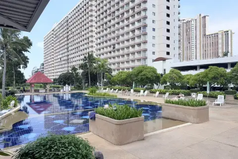 Rimhad Jomtien Condominium S2 pool area with planters, sun loungers and tall condo building