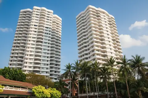 Royal Cliff Garden two white high-rise condo buildings with wavy balconies, palm trees, and lush greenery.