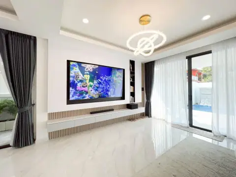 5 Bedroom House for Rent in Jomtien living area with large wall-mounted TV and sheer curtains