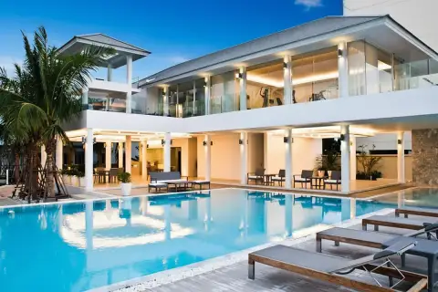 Sea Breeze Villa Pattaya expansive outdoor swimming pool area with modern villa, lounge chairs, and ocean view.
