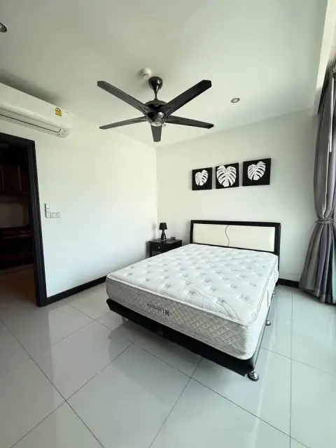 1 Bedroom Condo for Sale at Siam Ocean View bedroom with ceiling fan and leaf-themed wall art