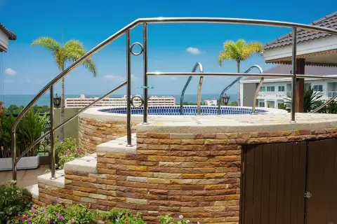 Siam Oriental Twins rooftop terrace with a small circular pool, stone wall, and ocean view in the background.