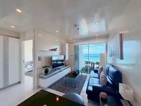 1 Bedroom Condo for Sale at Sky Residences Pattaya living room with leather sofa and sea view balcony
