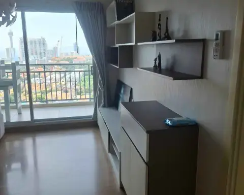 1 Bedroom Condo for Sale at Supalai Mare Pattaya living area with wall shelving, storage cabinet and balcony access