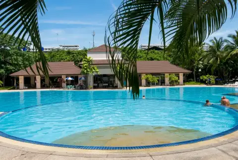 View Talay 1 circular swimming pool with poolside pavilion framed by palm leaves