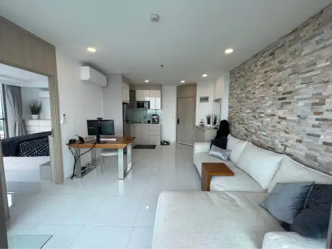 1 Bedroom Condo for Sale at The Cloud open living space with stone wall, sofa, desk, and view into kitchen and bedroom