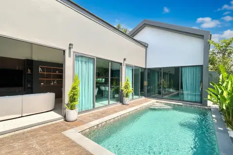 The Hamlet Pattaya, exterior view of a modern house with a private swimming pool, large sliding glass doors, and tropical plants.