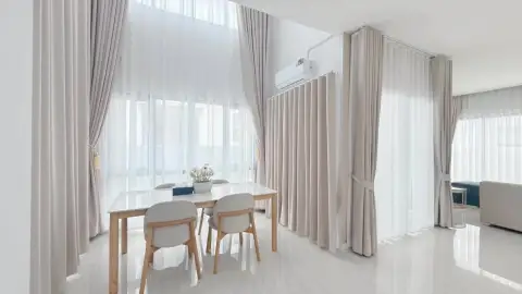 3 Bedroom House for Rent at The Palm Grandio's dining area with wooden table, chairs and sheer curtains