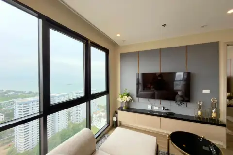 2 Bedroom Condo for Sale at The Panora Pattaya living room with wall-mounted TV and floor-to-ceiling sea view windows