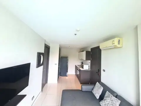 1 Bedroom Condo for Sale at The Point Pratumnak open-plan living area with kitchenette and gray sofa