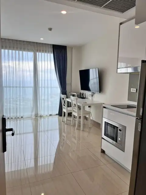 Studio Condo for Rent at The Riviera Jomtien kitchenette with microwave, dining table, and ocean view