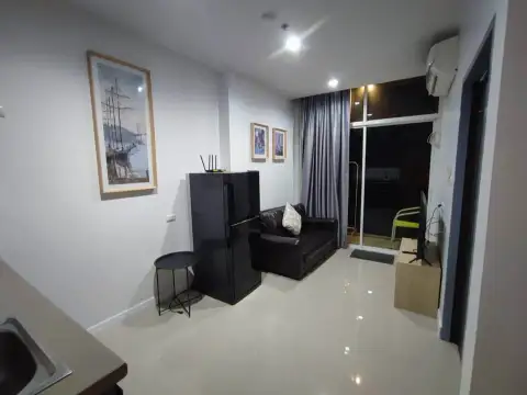 1 Bedroom Condo for Rent at The Twin Tower Jomtien Beach Pattaya living room with sofa, wall art, and balcony access at night