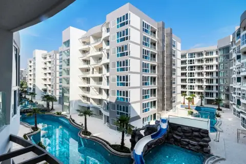 Grand Avenue Residence long, winding swimming pool with palm trees, lounge chairs, and condo building balconies.