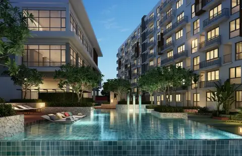 Stasia Dormy Residence evening view of courtyard pool with loungers and illuminated condo buildings