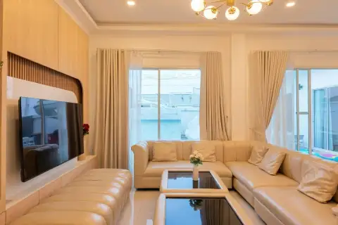 5 Bedroom House for Sale in Huai Yai bright living room with cream leather sectional sofa, TV wall and gold chandelier